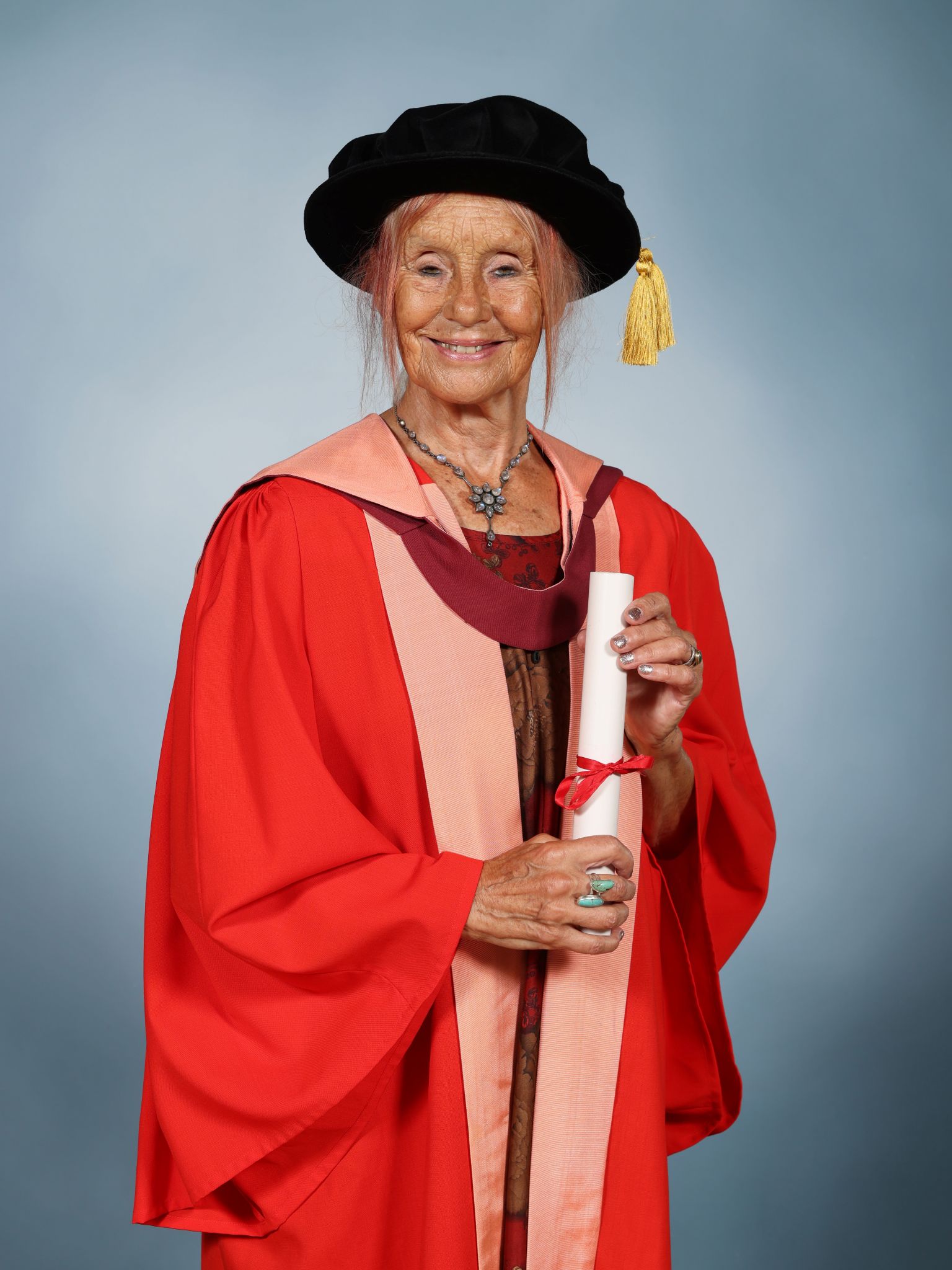 Professor Gill Hague CBE wearing a mortar board and holding a parchment
